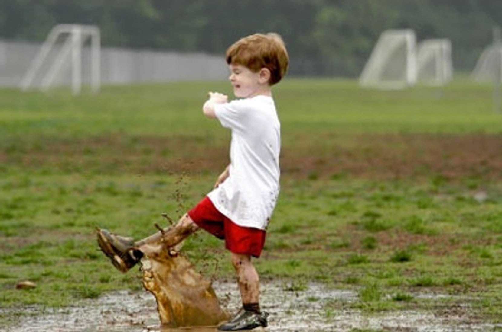 Boy splashing in muddy puddle.